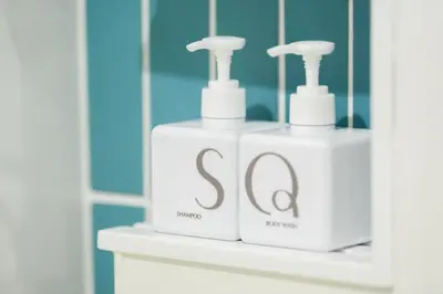 two white bottles of soap sitting on a shelf in a bathroom at SQ Boutique Hotel in Bangkok