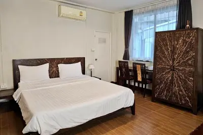 a bedroom with a large bed with white sheets and a window at Baan Glang Soi Restaurant & Guesthouse in Bangkok