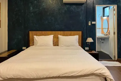 a bedroom with a large white bed with a blue wall at Baan Glang Soi Restaurant & Guesthouse in Bangkok