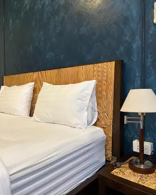 a bed with white pillows and a blue wall at Baan Glang Soi Restaurant & Guesthouse in Bangkok