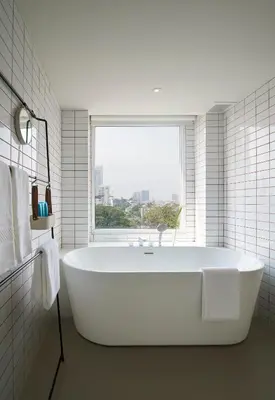 a white bath tub in a bathroom with a window at Shama Yen-Akat Bangkok in Bangkok