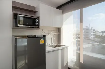 a kitchen with a refrigerator and a sink and a window at ORION Hotel & Residence Bangna in Bangkok