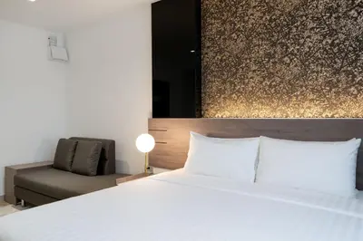 a bedroom with a white bed and a chair at ORION Hotel & Residence Bangna in Bangkok