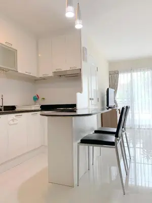 a white kitchen with a table and a black chair at Charming Resident near BTS Ekkamai Station in Bangkok