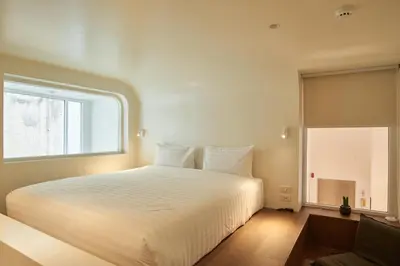 a bedroom with a white bed and a window at Bonsai Hotel Bangkok in Bangkok