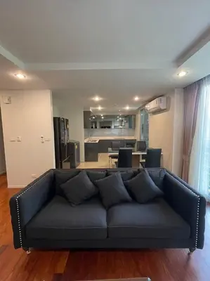 a black couch in a living room with a kitchen at ViVi Avenue Thonglor in Bangkok