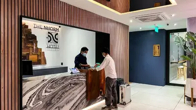 a man standing at a counter in a store at The Nhorm Hotel Ratchada in Bangkok