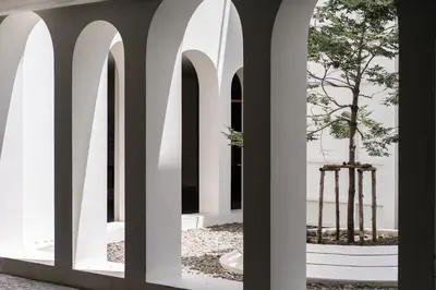 a hallway with arches and a tree in the middle at Away Bangkok Riverside Kene in Bangkok