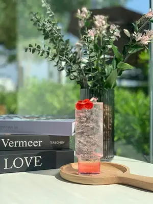 a vase with a red rose on a wooden coaster at Away Bangkok Riverside Kene in Bangkok