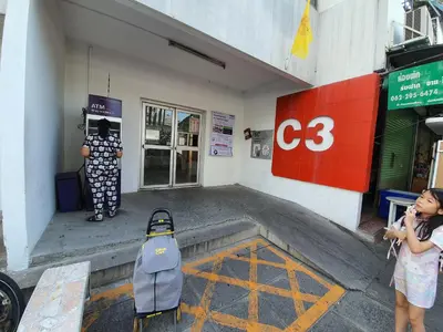 a woman is standing outside of a building with a suitcase at Great Location At IMPACT ARENA Muang Thong Thani C3 in Pak Kret