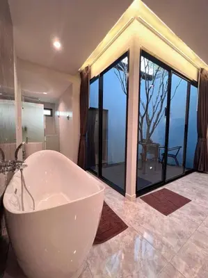 a bath tub in a bathroom with a large window at VEVILLA in Bangkok