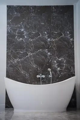 a black marble bathroom with a white tub at VEVILLA in Bangkok