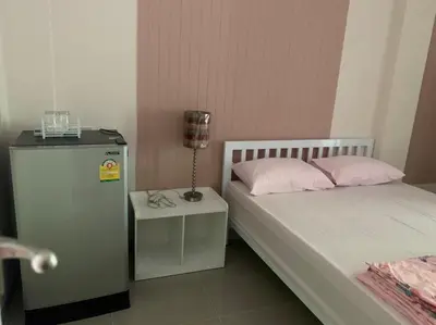 a bedroom with two beds and a table with a lamp at Firstbuild Apartment (เฟิร์สบิวท์อพาร์ทเม้น) in Bangkok