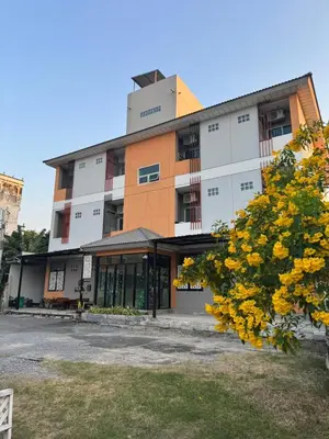 a building with a tree in front of it at Firstbuild Apartment (เฟิร์สบิวท์อพาร์ทเม้น) in Bangkok