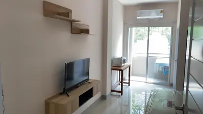 a living room with a flat screen tv on a wall at Firstbuild Apartment (เฟิร์สบิวท์อพาร์ทเม้น) in Bangkok