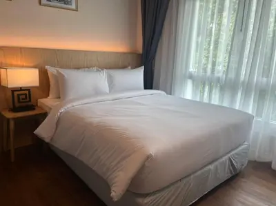 a bedroom with a large white bed with a window at Ago Hotel Chinatown in Bangkok