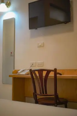 a chair sitting at a desk with a television on the wall at Ago Hotel Chinatown in Bangkok