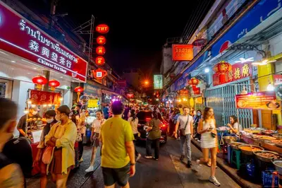 a group of people walking in a street at night at Ago Hotel Chinatown in Bangkok