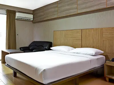 a bedroom with a large white bed and a chair at Watana Hotel in Bangkok