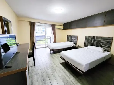 a hotel room with two beds and a table and a desk at Watana Hotel in Bangkok