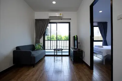 a living room with a couch and a bed and a mirror at Room 36 service apartment in Bangkok