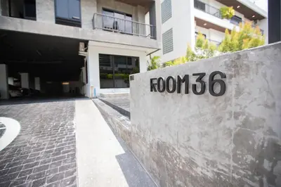 a stone wall with a sign that reads room at Room 36 service apartment in Bangkok