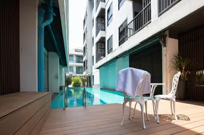 a pair of chairs sitting on a deck next to a swimming pool at Room 36 service apartment in Bangkok