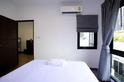 a bedroom with a white bed and a window at Room 36 service apartment in Bangkok