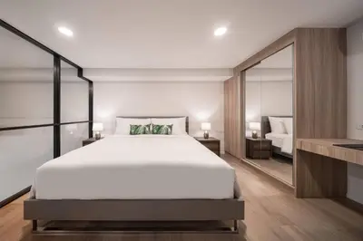 a bedroom with a large white bed and a mirror at Ramada By Wyndham Bangkok Sukhumvit 87 in Bangkok