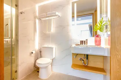 a white bathroom with a toilet and a sink at FX HOTEL NANA in Bangkok