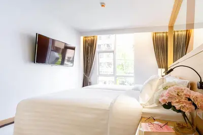 a bedroom with a large white bed and a tv at FX HOTEL NANA in Bangkok
