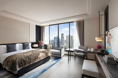 a bedroom with a bed and a desk and a large window at Ascott Thonglor Bangkok in Bangkok