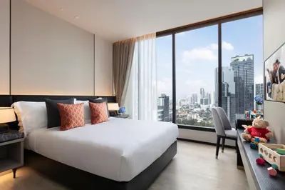 a bedroom with a bed and a large window at Ascott Thonglor Bangkok in Bangkok