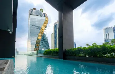 a swimming pool in a city with buildings at Ascott Thonglor Bangkok in Bangkok