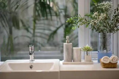 a bathroom sink with towels and a vase with flowers at Tiang Capsule in Bangkok