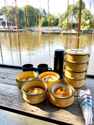four bowls of food sitting on a table near the water at Humz Canal Stay in Nonthaburi