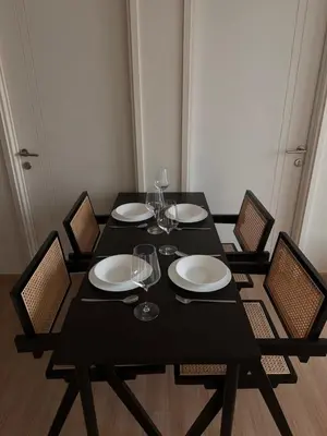 a black table with chairs and plates and wine glasses at Entire apartment near train station with pool & views in Ban Song Hong