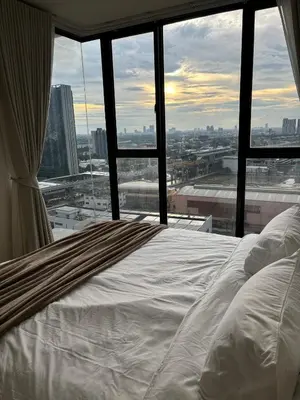 a bed in a room with a view of a city at Entire apartment near train station with pool & views in Ban Song Hong