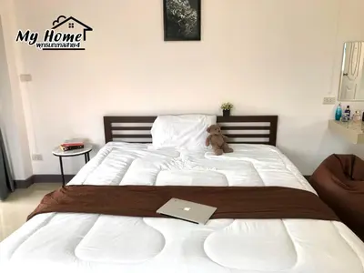 a teddy bear sitting on a bed with a laptop at MY HOME Hotel - Phutthamonthon 4 Road, near Mahidol University Salaya in Ban Krathum Lom