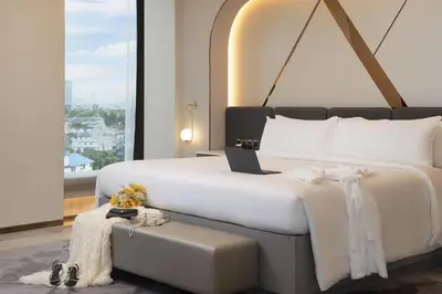 a bedroom with a large white bed and a window at Asawin Grand Convention Hotel in Bangkok