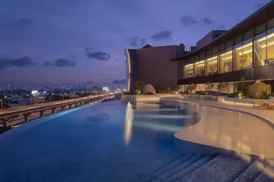 a swimming pool on top of a building at night at Asawin Grand Convention Hotel in Bangkok