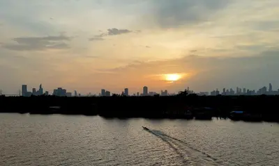 a boat in the water with a city in the background at Coconut Lane Bangkok in Bangkok