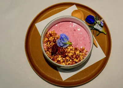 a bowl of food on a plate with a pink drink at Coconut Lane Bangkok in Bangkok