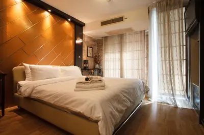 a bedroom with a large bed with a wooden headboard at Harmony Living Condominium in Makkasan