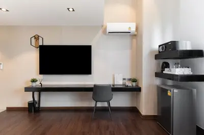 a desk with a tv and a chair in a room at โรงแรมอินฟินิทเกษตร in Ban Yang