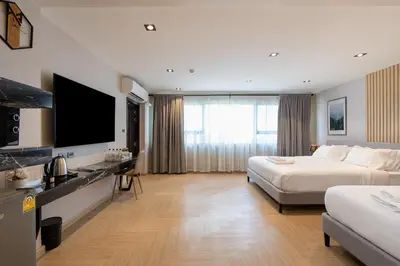 a hotel room with two beds and a flat screen tv at โรงแรมอินฟินิทเกษตร in Ban Yang