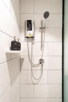 a white bathroom with a shower with a shower head at โรงแรมอินฟินิทเกษตร in Ban Yang