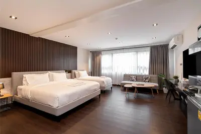 a hotel room with two beds and a television at โรงแรมอินฟินิทเกษตร in Ban Yang