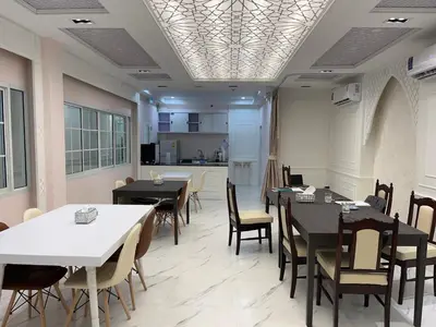 a dining room with tables and chairs and a kitchen at Anwari Hotel in Bangkok
