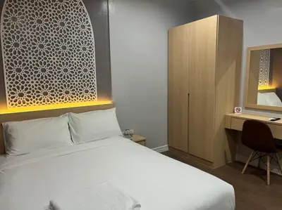 a bedroom with a bed and a desk and a cabinet at Anwari Hotel in Bangkok